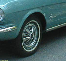 Closeup of front fender of a six cylinder Ford Mustang. There is a running Mustang badge behind the wheel well, but nothing in front of the wheel well.