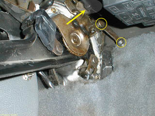 Detail of parking brake pedal area beneath the dash, showing the end of the release cable, the bracket for holding the cable housing, and the slotted end for the bead on the end of the cable itself.