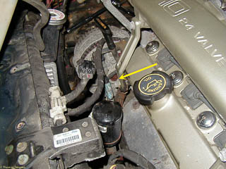 Rear of the alternator still in place. Arrow points to bolt in the rear that must be removed.