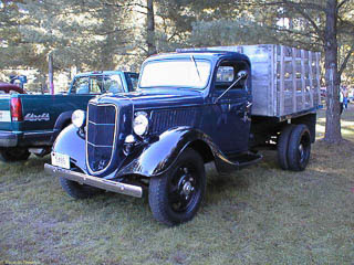 Drivers side view of 1936 Ford 1 1/2 ton truck. Dual wheels in back with a wood stake bed.